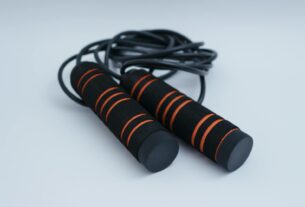 A minimalist close-up of black and orange exercise skipping rope on a clean white background.