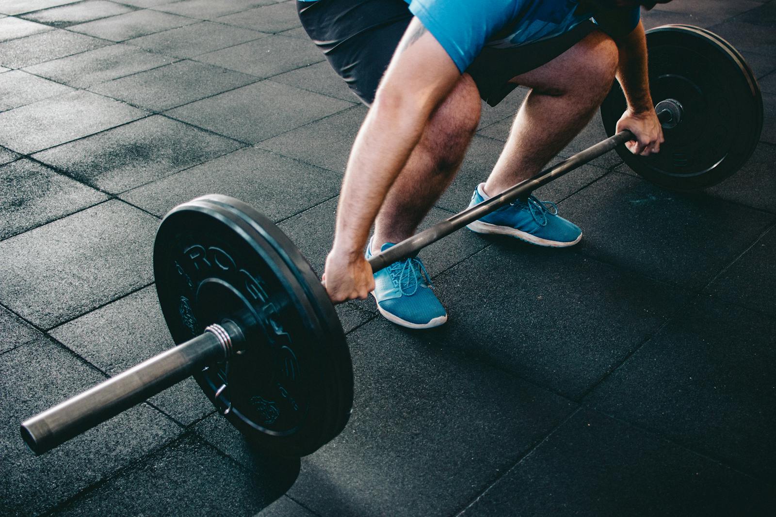 A man deadlifting a barbell indoors showcasing power, fitness, and dedication.