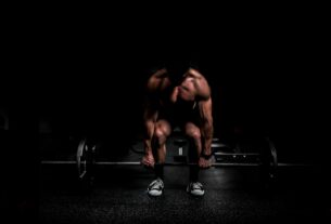 topless man in black shorts sitting on black and silver barbell